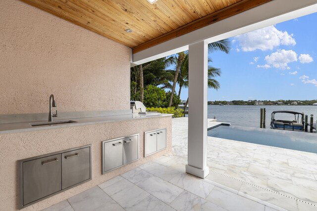103 River Dr, Tequesta, FL 33469 - view of patio featuring a sink, an outdoor kitchen, and a water view