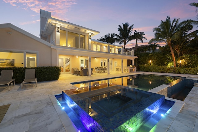 103 River Dr, Tequesta, FL 33469 - back of property with stucco siding, a patio, a pool with connected hot tub, and an outdoor living space