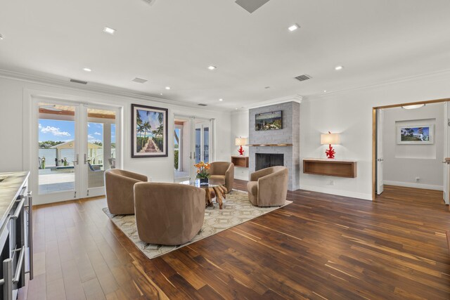 103 River Dr, Tequesta, FL 33469 - living area featuring french doors, crown molding, dark wood-type flooring, a large fireplace, and recessed lighting