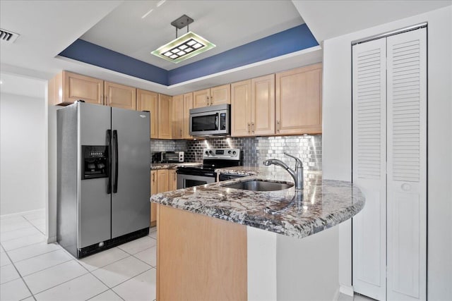 1640 Twelve Oaks Way Unit 205, North Palm Beach, FL 33408 - kitchen with backsplash, appliances with stainless steel finishes, light stone counters, light brown cabinets, and a tray ceiling
