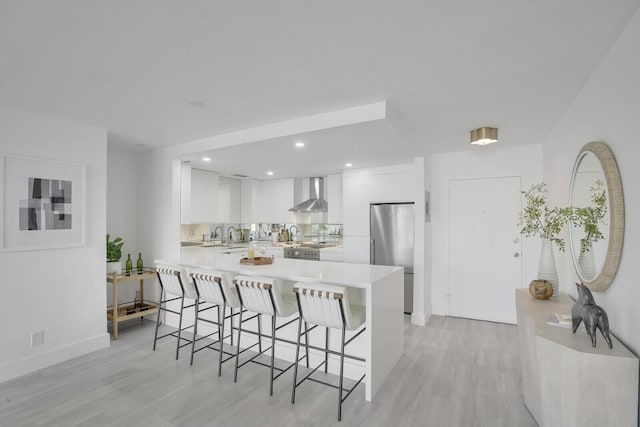 354 Chilean Ave Unit 4D, Palm Beach, FL 33480 - kitchen featuring wall chimney exhaust hood, stainless steel refrigerator, a breakfast bar area, light countertops, and recessed lighting