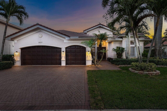 8837 Woodgrove Ridge Ct, Boynton Beach, FL 33473 - mediterranean / spanish-style home featuring an attached garage, decorative driveway, a front lawn, and stucco siding