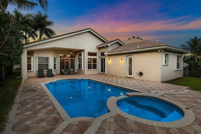 8837 Woodgrove Ridge Ct, Boynton Beach, FL 33473 - back of house at dusk with a patio, a pool with connected hot tub, a ceiling fan, and stucco siding