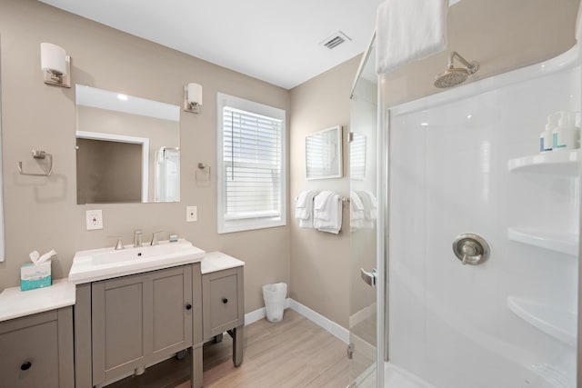 full bath with baseboards, vanity, wood finished floors, and a shower stall