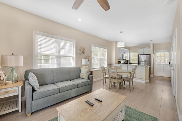 living room featuring a ceiling fan and baseboards