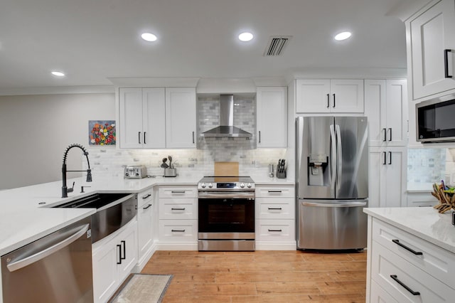 kitchen featuring backsplash, visible vents, appliances with stainless steel finishes, a sink, and wall chimney exhaust hood