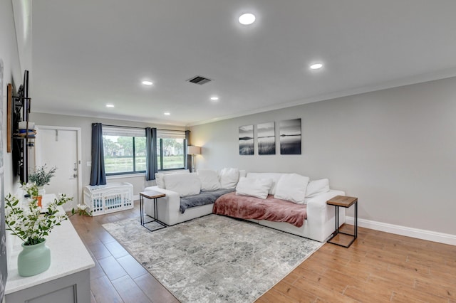 living room featuring visible vents, light wood-type flooring, baseboards, ornamental molding, and recessed lighting