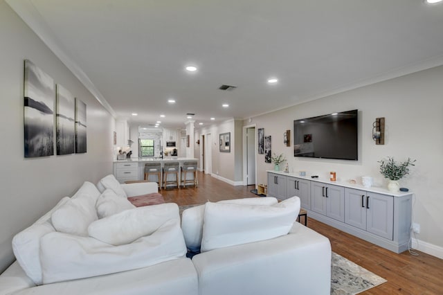 living area featuring crown molding, recessed lighting, visible vents, and wood finished floors