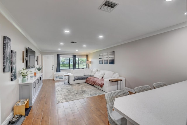 living area featuring visible vents, ornamental molding, recessed lighting, and light wood-type flooring