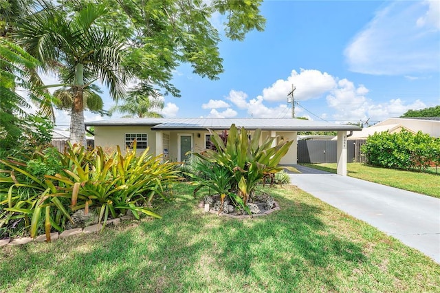 ranch-style home featuring driveway, a front yard, fence, an attached carport, and stucco siding