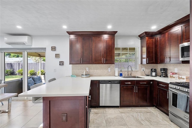 kitchen with a peninsula, light countertops, a wall unit AC, a sink, and stainless steel appliances