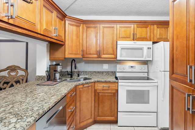 712 Sunny Pine Way Unit D1, Greenacres, FL 33415 - kitchen with a textured ceiling, brown cabinets, a sink, light stone counters, and white appliances