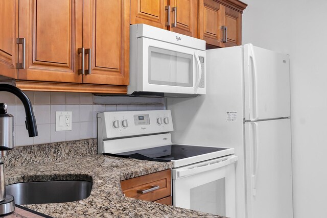 712 Sunny Pine Way Unit D1, Greenacres, FL 33415 - kitchen with brown cabinets, light stone countertops, a sink, white appliances, and tasteful backsplash