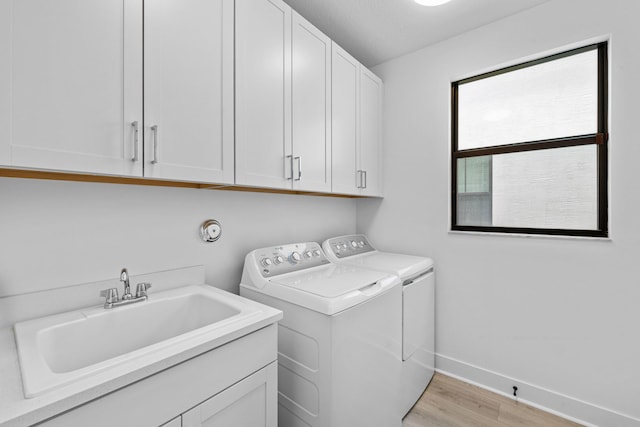 13158 Artisan Cir, Palm Beach Gardens, FL 33418 - washroom with washing machine and clothes dryer, light wood-style flooring, cabinet space, and baseboards