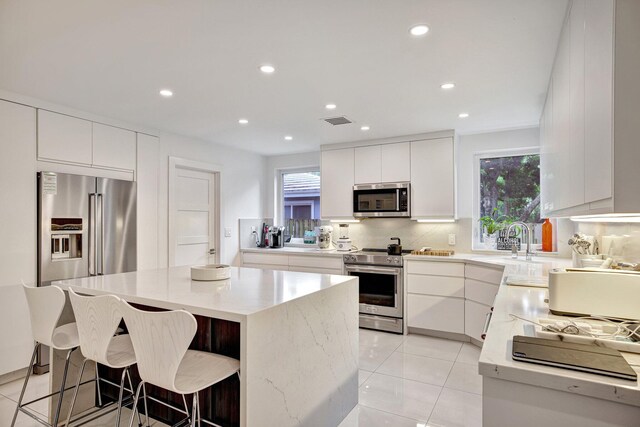 kitchen featuring recessed lighting, appliances with stainless steel finishes, a center island, and a kitchen bar