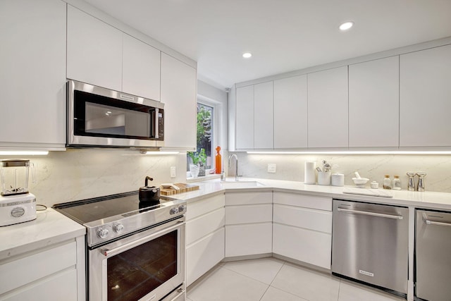 kitchen with backsplash, white cabinets, appliances with stainless steel finishes, and modern cabinets