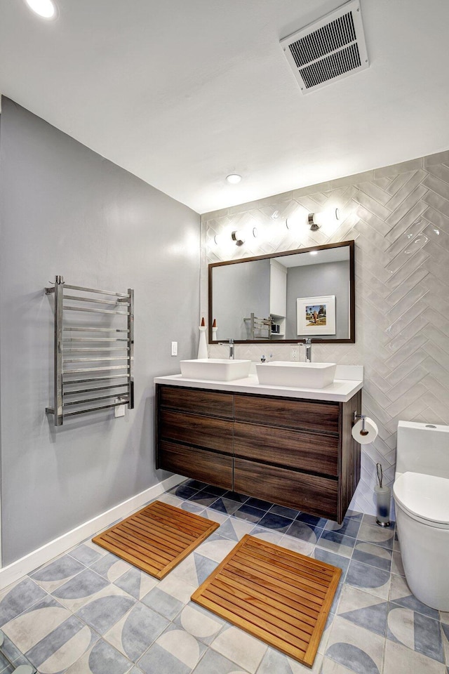 full bathroom featuring double vanity, visible vents, a sink, toilet, and radiator