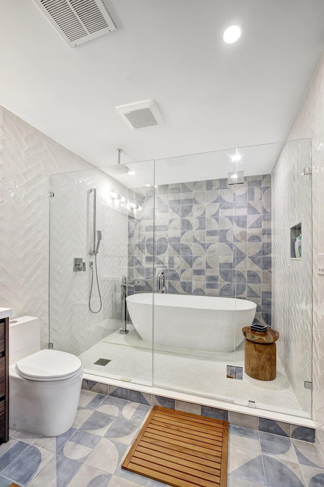 bathroom with tile walls, a shower stall, and visible vents