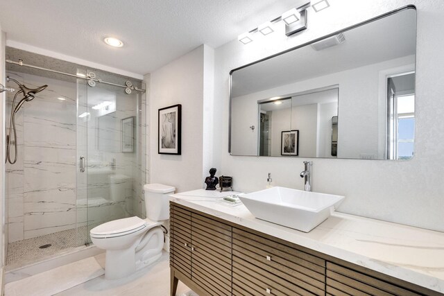 full bathroom featuring toilet, a marble finish shower, and vanity