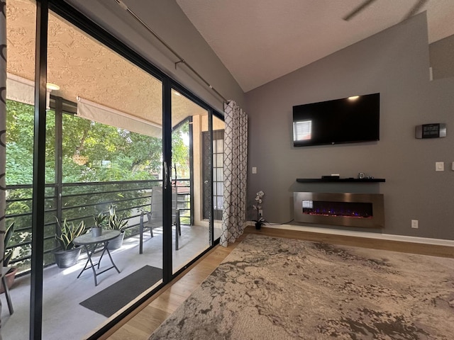13 Via De Casas Sur Unit 203, Boynton Beach, FL 33426 - doorway to outside featuring a lit fireplace, vaulted ceiling, and wood finished floors
