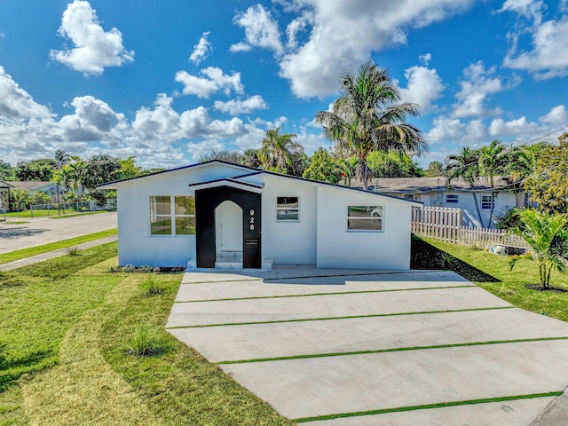 928 Market St, West Palm Beach, FL 33401 - view of front facade featuring concrete driveway, fence, a front lawn, and stucco siding