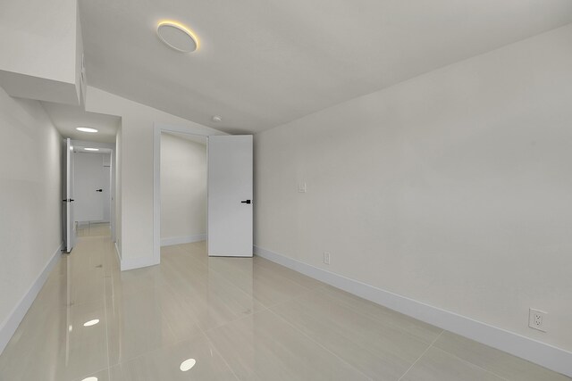 928 Market St, West Palm Beach, FL 33401 - unfurnished bedroom with light tile patterned flooring, baseboards, and vaulted ceiling