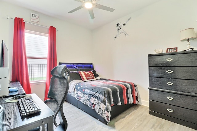 bedroom featuring ceiling fan, baseboards, multiple windows, and wood finished floors