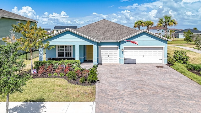 view of front facade featuring decorative driveway, fence, a front lawn, an attached garage, and a shingled roof
