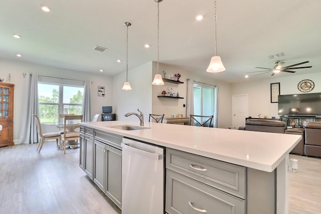kitchen featuring a sink, dishwashing machine, open floor plan, and gray cabinetry