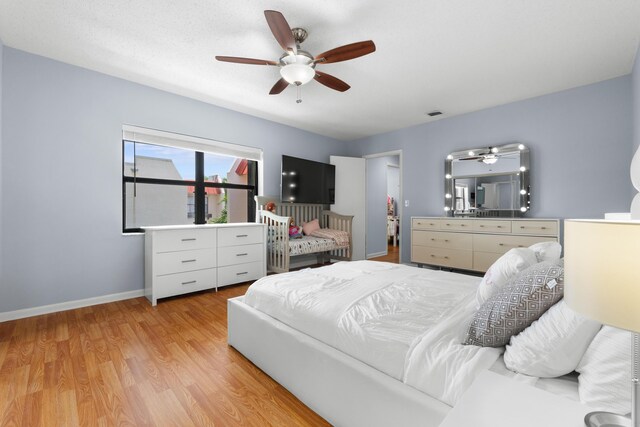 bedroom with baseboards, a ceiling fan, light wood-type flooring, and visible vents
