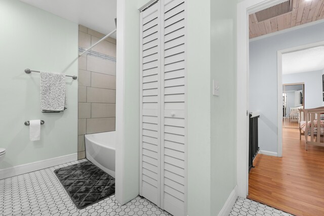bathroom with baseboards, shower / bath combination, visible vents, and toilet