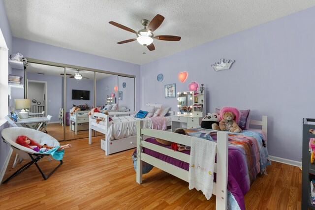 bedroom with light wood-style floors, ceiling fan, a closet, and a textured ceiling