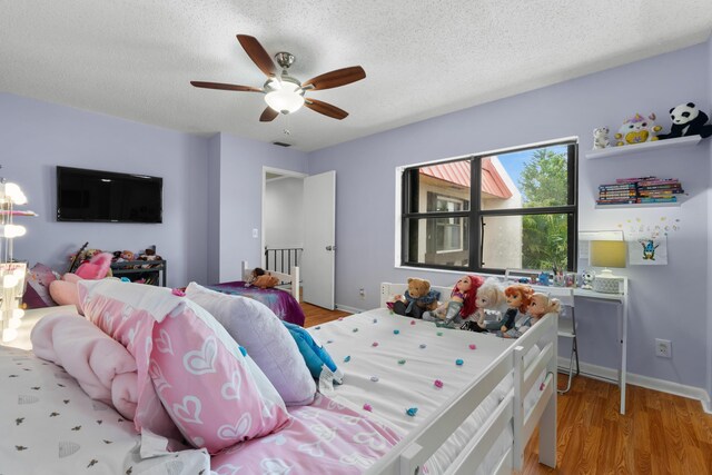 bedroom with baseboards, a textured ceiling, light wood finished floors, and ceiling fan