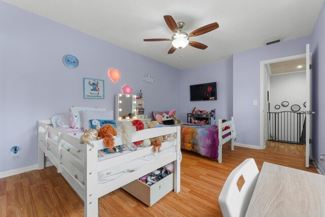 bedroom with baseboards, ceiling fan, wood finished floors, and visible vents