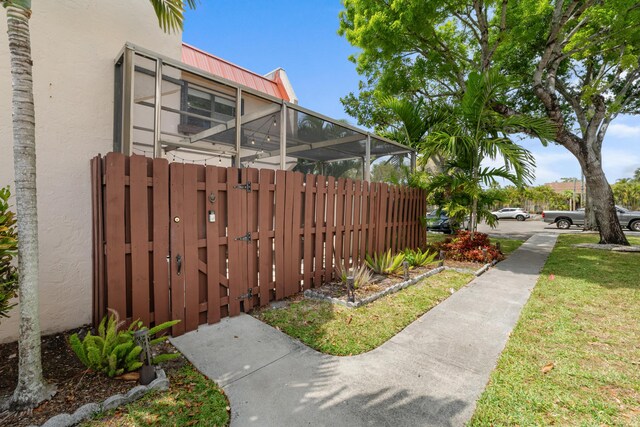 view of yard featuring fence, a gate, and glass enclosure