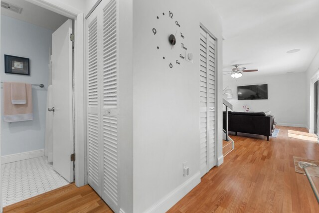 hallway with baseboards, light wood-style flooring, and visible vents