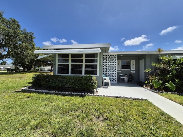 rear view of property with a lawn and stucco siding