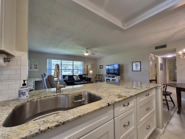 kitchen with a sink, a ceiling fan, white cabinets, and open floor plan