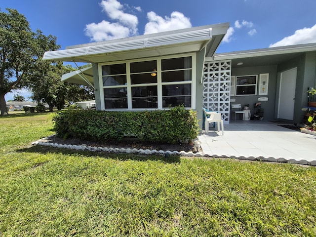 rear view of house featuring stucco siding and a yard
