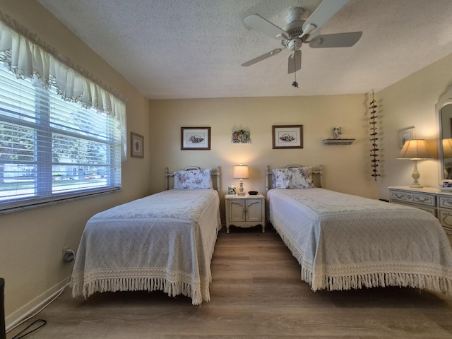 bedroom with a textured ceiling, a ceiling fan, and wood finished floors