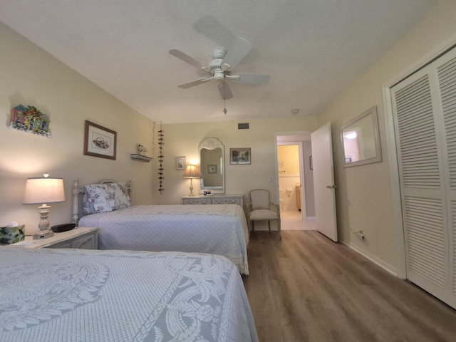 bedroom with a ceiling fan, visible vents, wood finished floors, baseboards, and a closet
