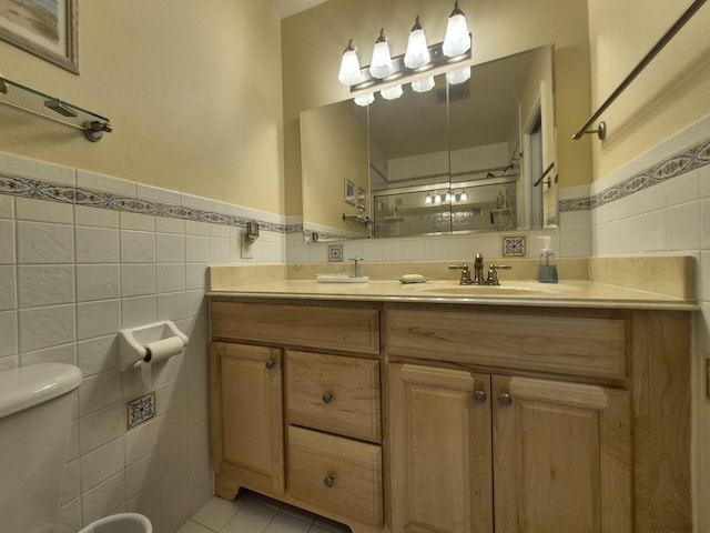 bathroom with vanity, tile patterned flooring, toilet, tile walls, and a wainscoted wall