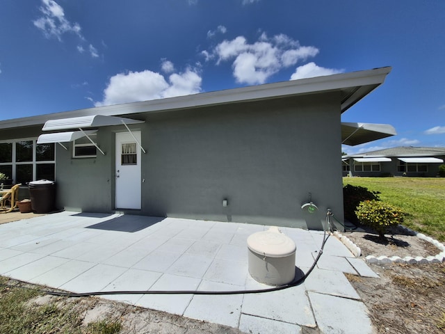 back of property with stucco siding and a patio area