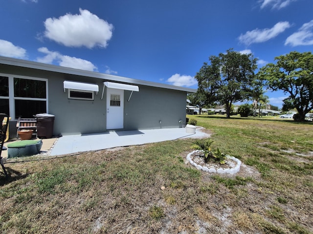 back of property with a lawn, a patio, and stucco siding