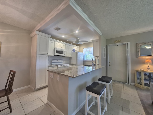 kitchen featuring visible vents, white appliances, a textured ceiling, white cabinetry, and a sink