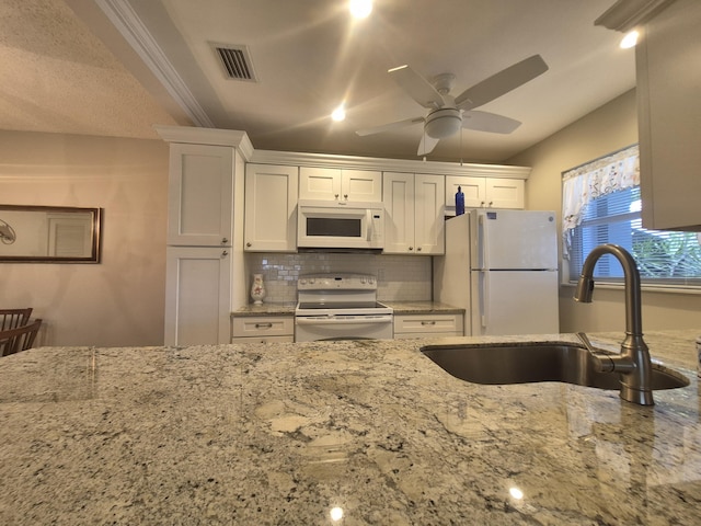 kitchen featuring white cabinets, light stone countertops, a sink, white appliances, and visible vents