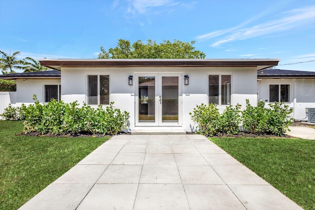 2410 SW 1st St, Boynton Beach, FL 33435 - back of house featuring a lawn, stucco siding, and french doors