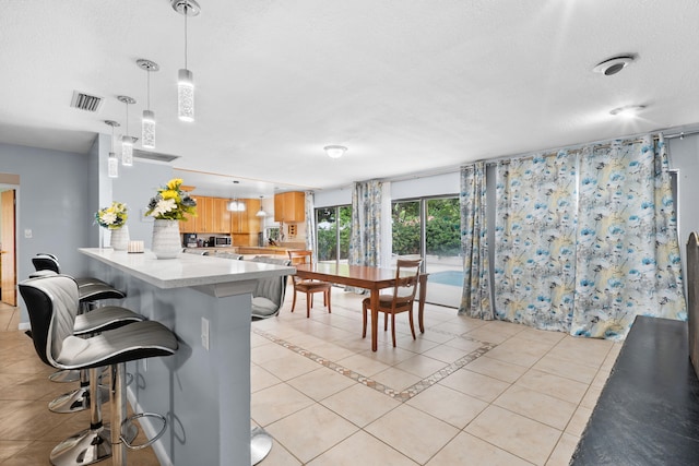 115 NE Caprona Ave, Port Saint Lucie, FL 34983 - kitchen featuring a peninsula, a breakfast bar, visible vents, light countertops, and light tile patterned floors
