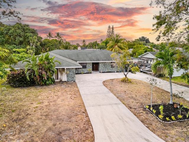 115 NE Caprona Ave, Port Saint Lucie, FL 34983 - ranch-style home featuring stone siding, a chimney, and curved driveway