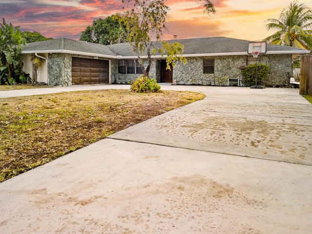 115 NE Caprona Ave, Port Saint Lucie, FL 34983 - view of front of property featuring stone siding, driveway, and a garage